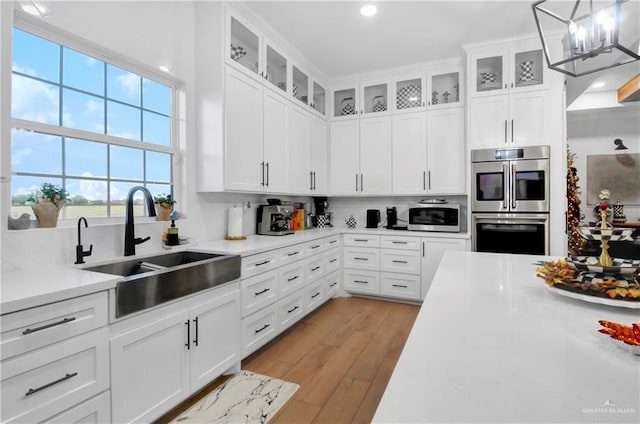 kitchen with white cabinetry, sink, stainless steel appliances, and light wood-type flooring