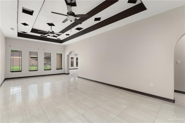 tiled empty room with ceiling fan and a tray ceiling