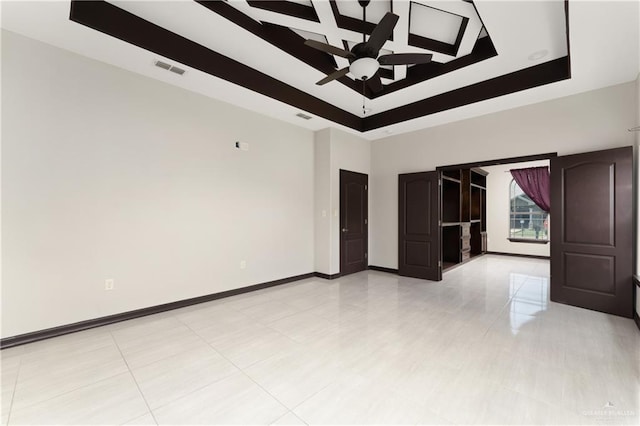 tiled spare room featuring ceiling fan and a tray ceiling