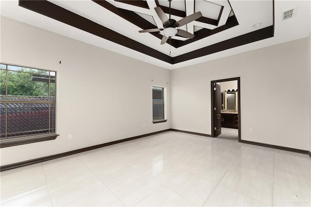 tiled spare room with a tray ceiling and ceiling fan