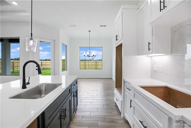 kitchen featuring pendant lighting, light countertops, a sink, and white cabinetry