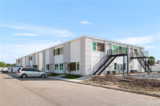 view of building exterior with uncovered parking and stairway