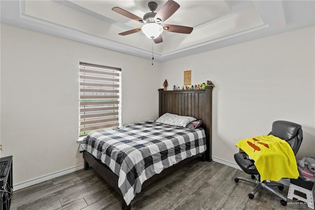 bedroom featuring dark hardwood / wood-style floors, ceiling fan, and a tray ceiling