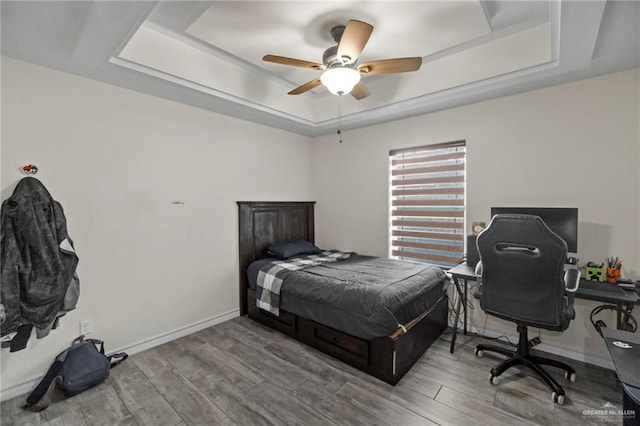 bedroom with a raised ceiling, ceiling fan, and hardwood / wood-style floors