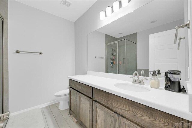 bathroom with vanity, tile patterned floors, a shower with door, and toilet