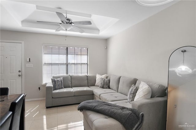 tiled living room featuring a raised ceiling and ceiling fan