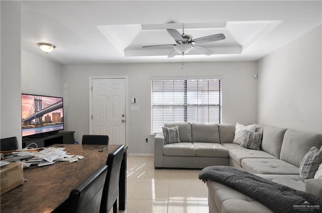 tiled living room with a raised ceiling and ceiling fan