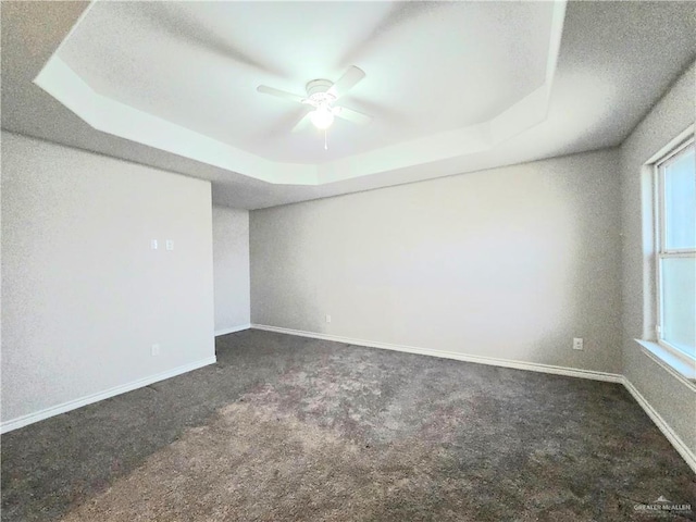 unfurnished room featuring carpet floors, baseboards, a tray ceiling, and ceiling fan