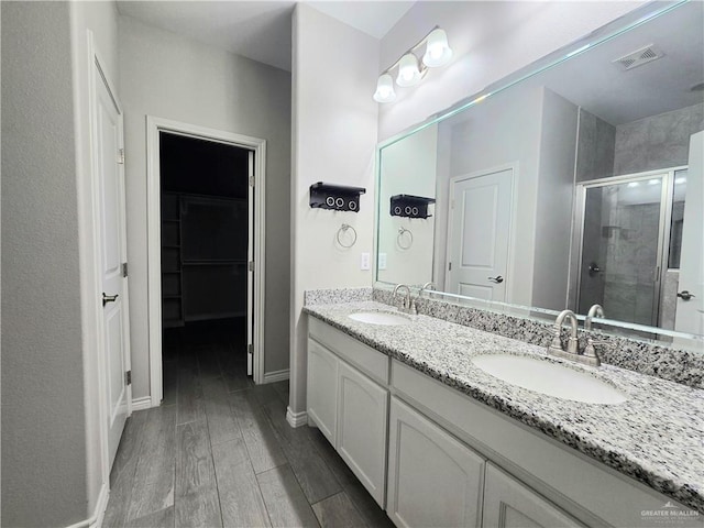 bathroom with a shower stall, visible vents, a sink, and wood finished floors