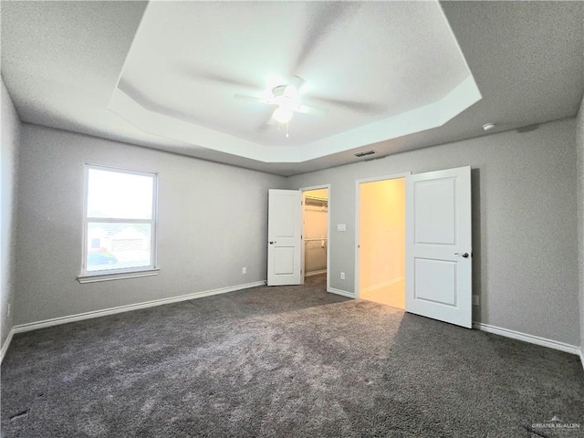 unfurnished bedroom featuring a tray ceiling, carpet flooring, visible vents, and baseboards