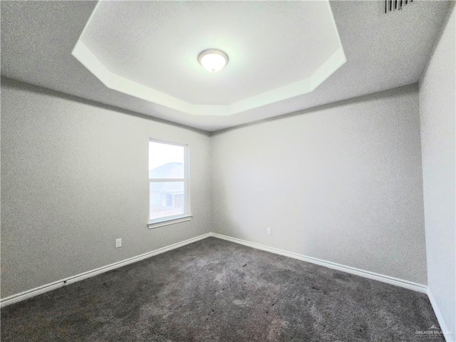 unfurnished room featuring a raised ceiling, carpet flooring, visible vents, and baseboards