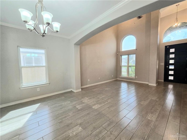 entrance foyer featuring wood finished floors, crown molding, and an inviting chandelier