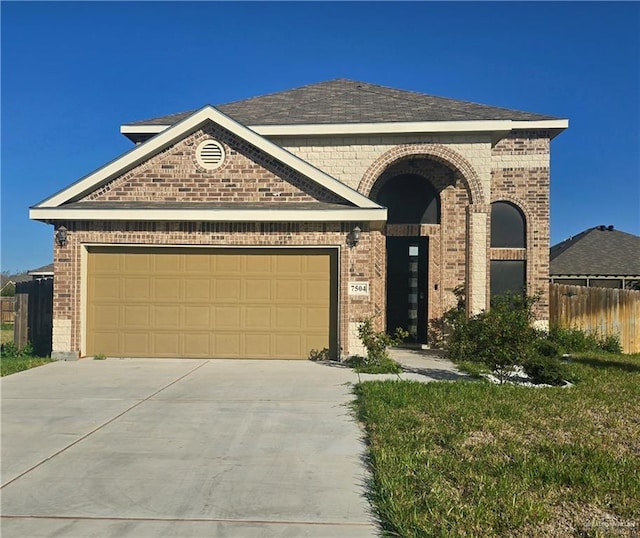 view of front of home with driveway, brick siding, an attached garage, and fence