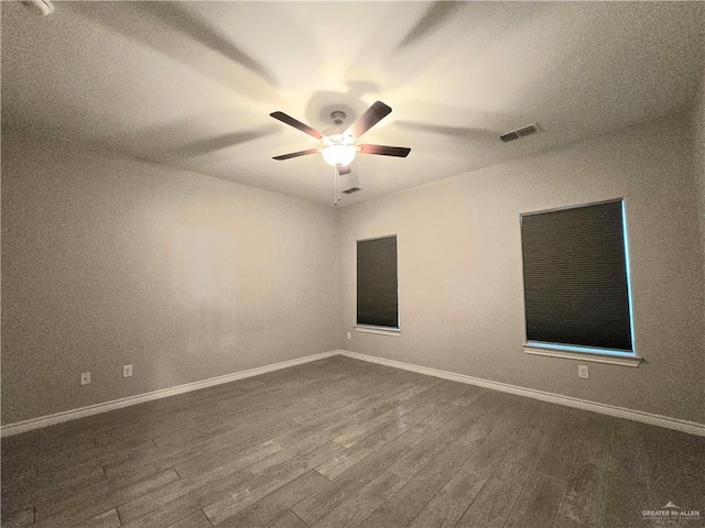 unfurnished room featuring dark wood-style flooring, visible vents, ceiling fan, and baseboards