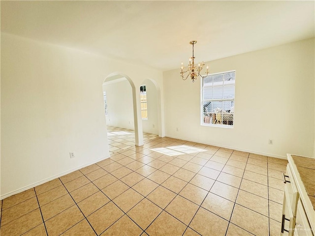 empty room with light tile patterned floors and a chandelier