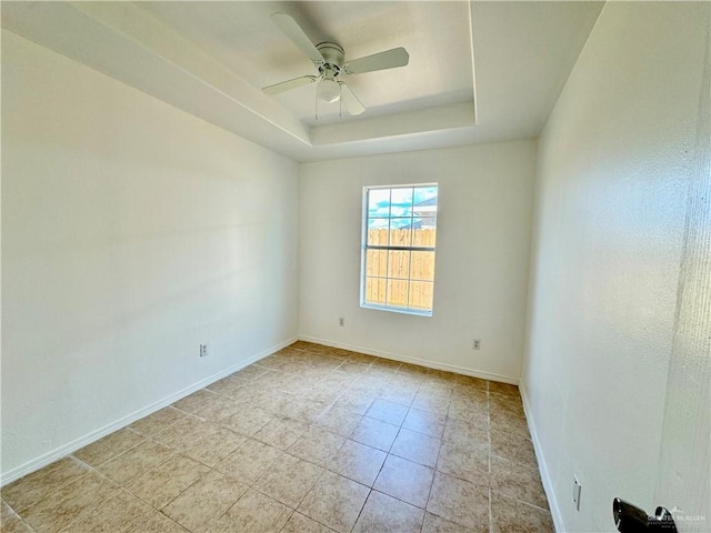 spare room featuring ceiling fan and a raised ceiling