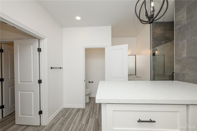 full bath with vanity, baseboards, a chandelier, toilet, and tiled shower