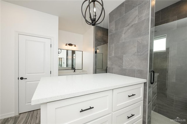 full bathroom featuring vanity, an inviting chandelier, a stall shower, and wood finished floors