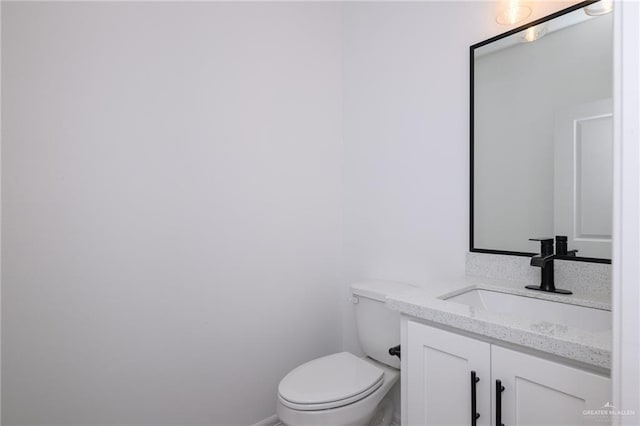half bath featuring vanity, baseboards, and toilet