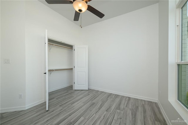unfurnished bedroom featuring a closet, baseboards, a ceiling fan, and wood finished floors