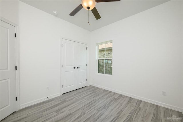 unfurnished bedroom with a closet, light wood finished floors, baseboards, and ceiling fan