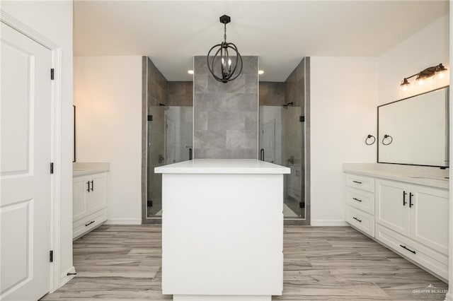 bathroom with a stall shower, two vanities, wood finished floors, and baseboards