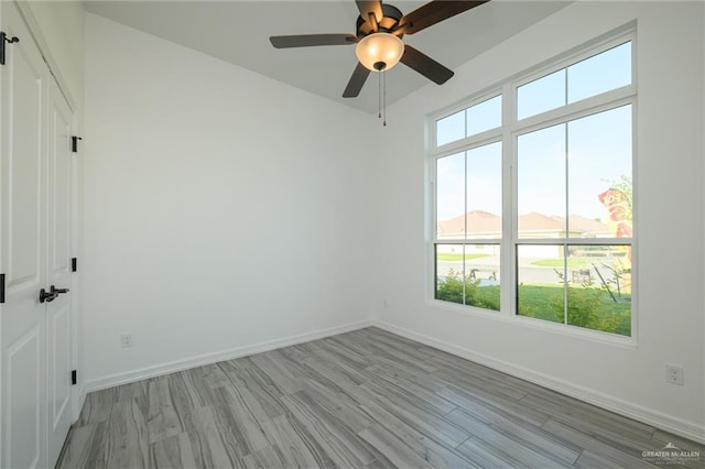 spare room with light wood-style flooring, baseboards, and a ceiling fan