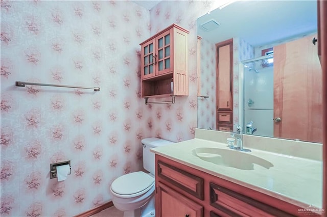 bathroom featuring vanity, toilet, and a shower with shower door