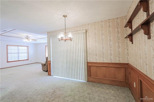 spare room with a textured ceiling, light carpet, and ceiling fan with notable chandelier