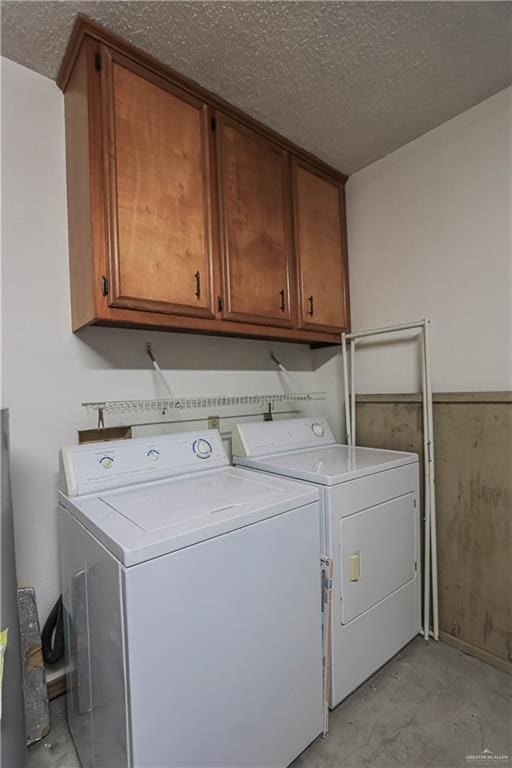 washroom featuring washer and dryer, cabinets, and a textured ceiling