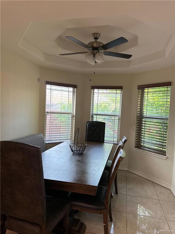 dining room featuring light tile patterned floors, a ceiling fan, a raised ceiling, and baseboards