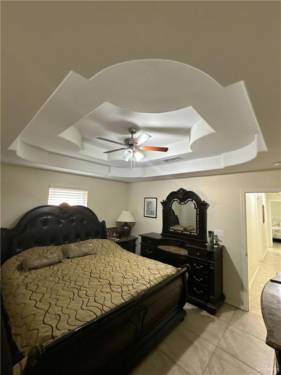 bedroom featuring visible vents, a ceiling fan, and a tray ceiling