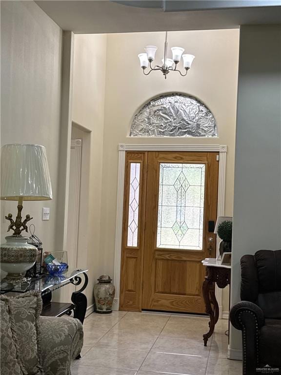 foyer entrance with light tile patterned floors, a towering ceiling, a notable chandelier, and baseboards
