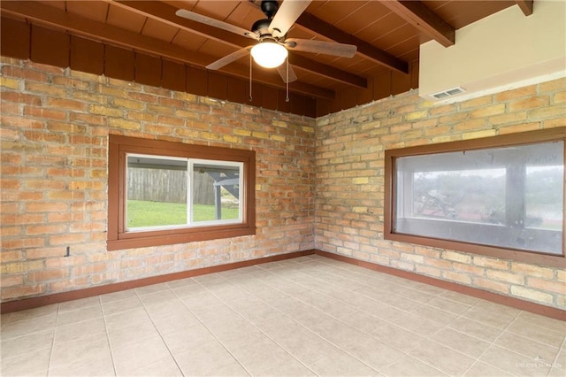 spare room with brick wall, beamed ceiling, light tile patterned floors, wood ceiling, and ceiling fan