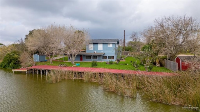 back of house with a water view and a lawn