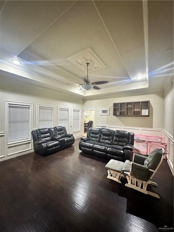 living room with crown molding, ceiling fan, a raised ceiling, and hardwood / wood-style floors