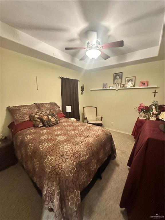 bedroom with a tray ceiling, light colored carpet, and ceiling fan