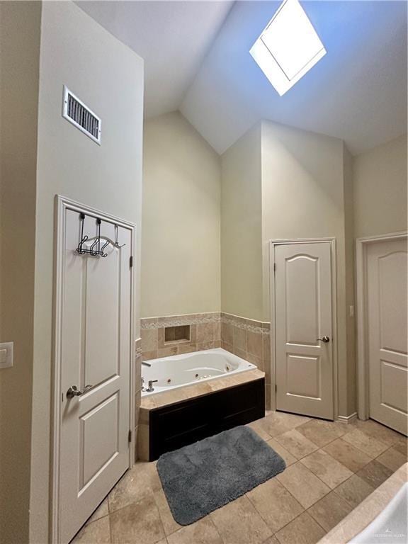 bathroom with a washtub, tile patterned floors, and vaulted ceiling with skylight