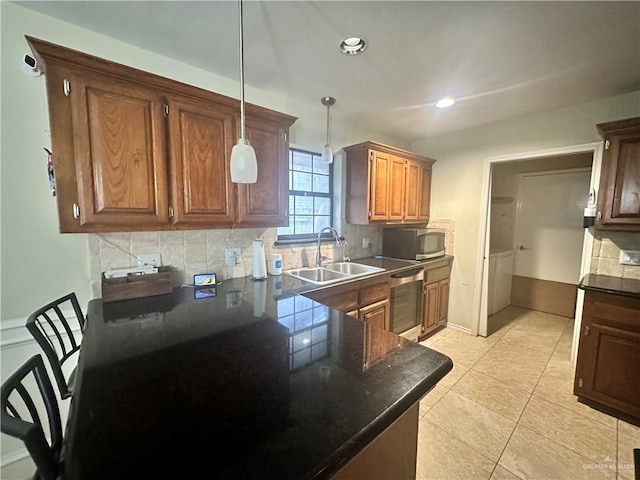 kitchen featuring tasteful backsplash, sink, dishwashing machine, and decorative light fixtures