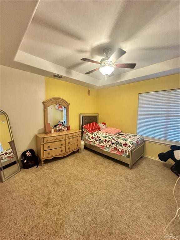 bedroom with carpet floors, a raised ceiling, and ceiling fan