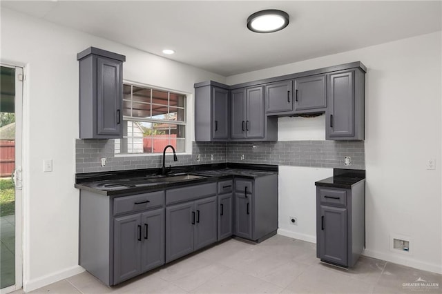 kitchen featuring decorative backsplash, light tile patterned floors, gray cabinetry, and sink