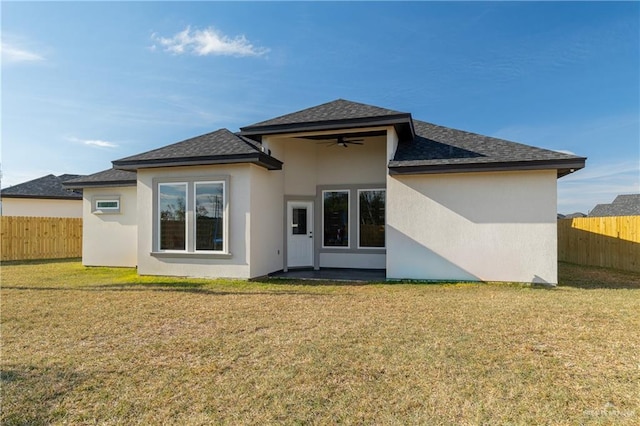 back of property featuring roof with shingles, stucco siding, a lawn, a ceiling fan, and a fenced backyard