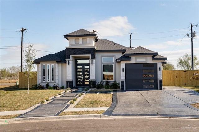 prairie-style home with french doors, stucco siding, an attached garage, fence, and driveway