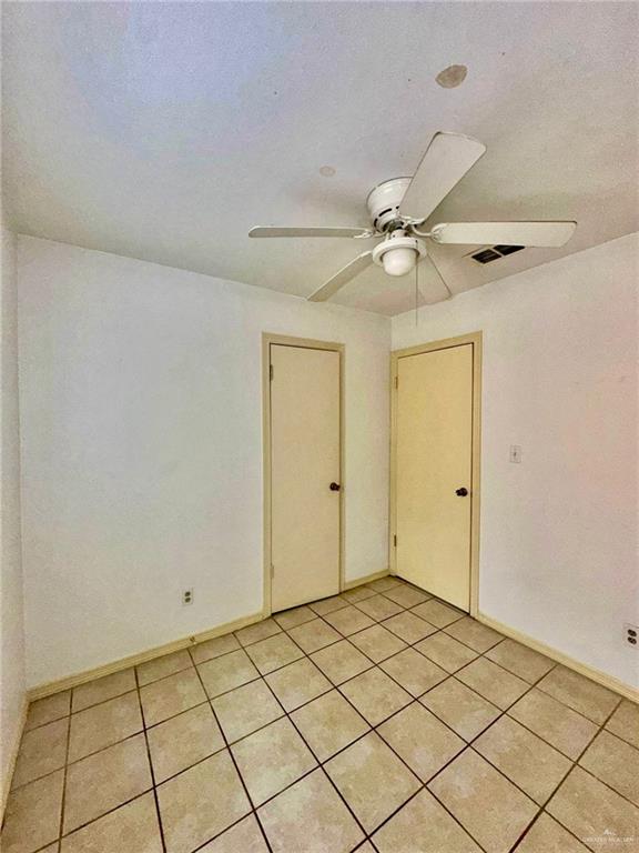 empty room with ceiling fan and light tile patterned flooring