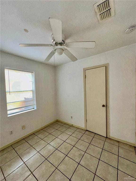 tiled spare room featuring ceiling fan