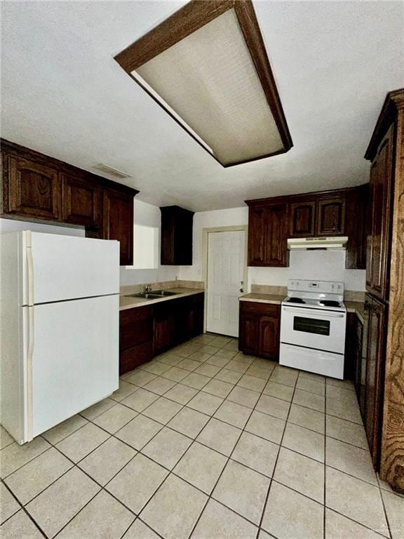 kitchen with dark brown cabinetry, white appliances, and sink