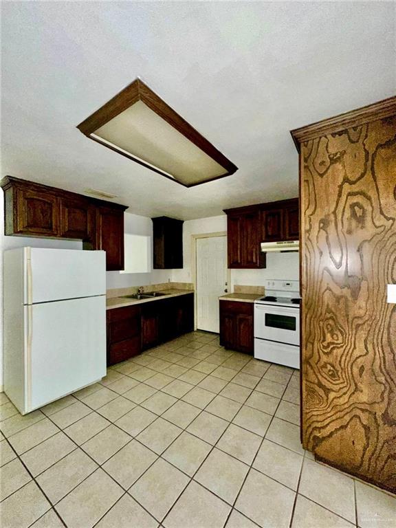 kitchen with sink, light tile patterned floors, and white appliances