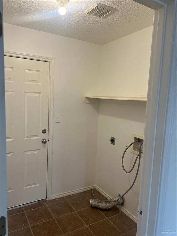 washroom with dark tile patterned floors, washer hookup, a textured ceiling, and hookup for an electric dryer