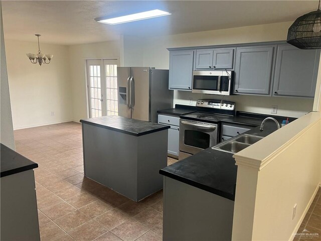 kitchen with french doors, an inviting chandelier, sink, appliances with stainless steel finishes, and a kitchen island