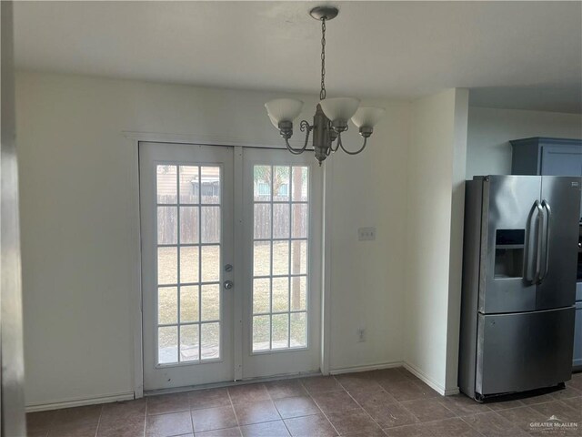 doorway with tile patterned floors, a wealth of natural light, and an inviting chandelier